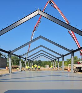 Construction workers laying concrete in a large indtustrial structure